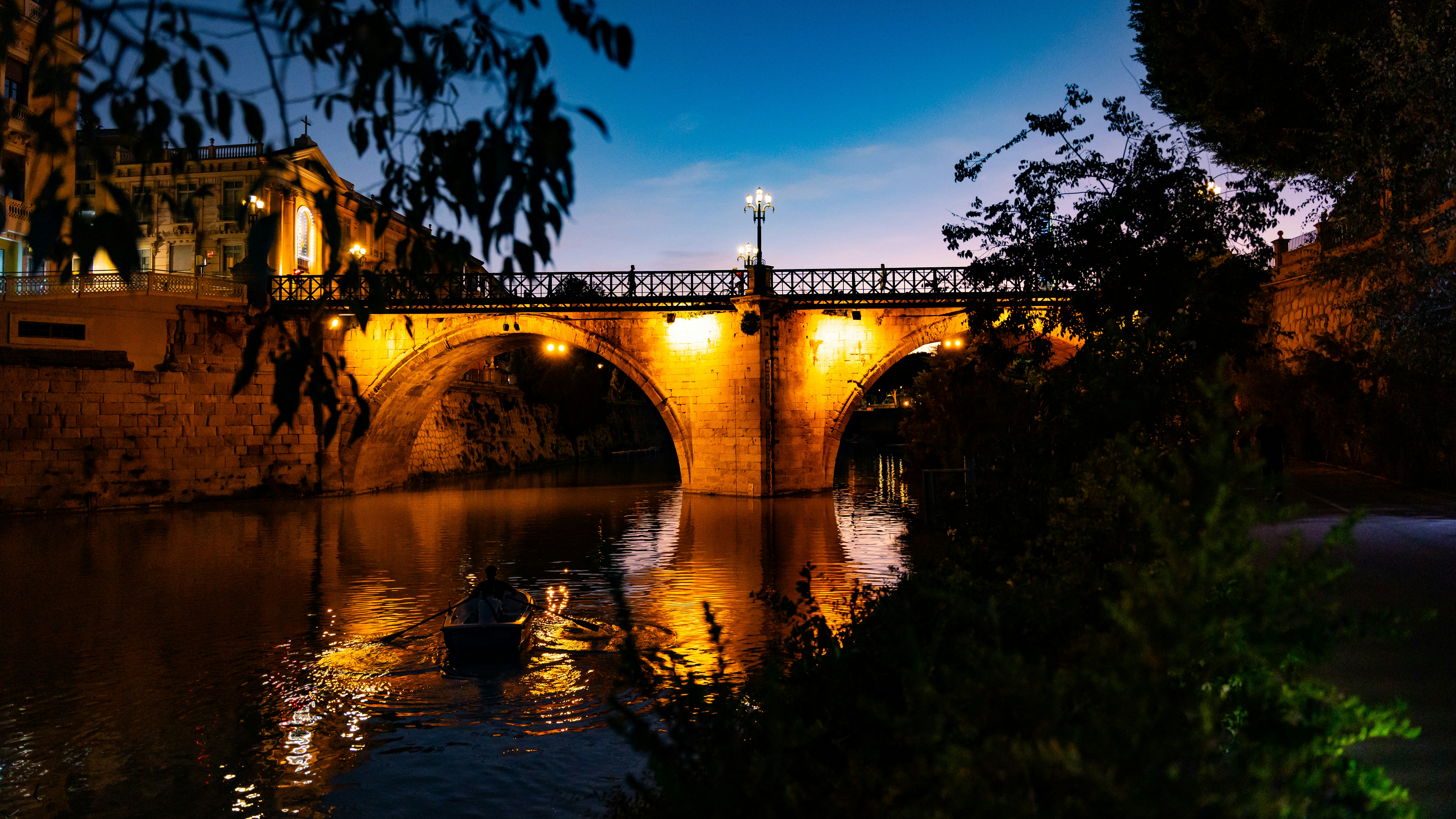 Evening view of a lit bridge over the river in Murcia, adding atmosphere to a food and wine city break.